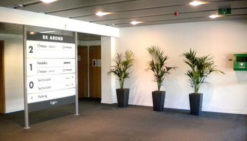 Ingang van een kantoor te huur op Blarenberglaan 2c, Mechelen Noord met strakke bewegwijzering en planten tegen een witte muur.