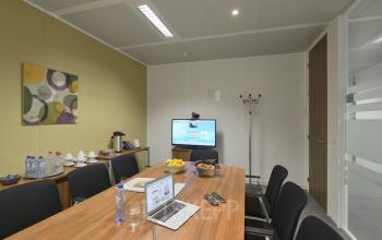 Vergaderruimte in te huren kantoor op Keizer Karellaan 584 in Sint-Agatha-Berchem, met lange tafel, stoelen en audiovisuele apparatuur.