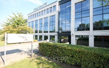 Kantoor te huur aan de Zuiderlaan 91, Zellik. Modern gebouw met veel glas en witte gevel, omringd door groen.